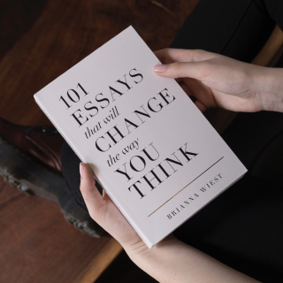 White book being held up on dark background, with title 101 Essays That Will Change The Way You Think by Brianna Wiest