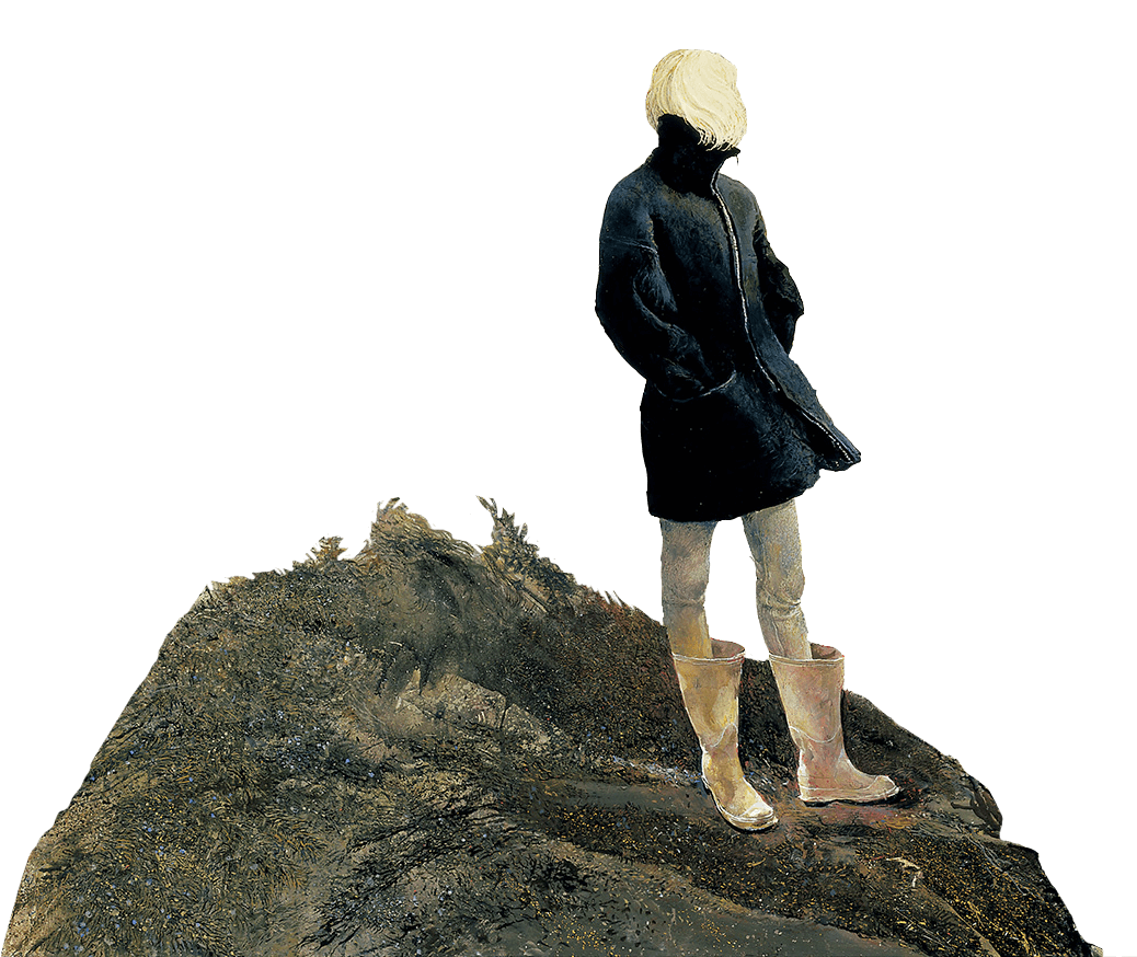 Woman with blonde hair, wearing a thick coat and knee high wellington boots, stands on a large rock looking into the distance